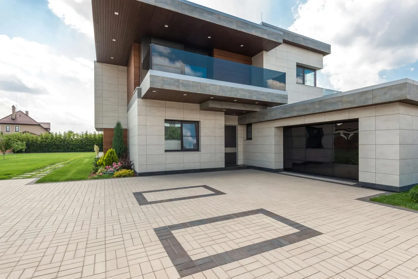 A modern home clad in large-format stone-look panels with a patterned paved driveway.