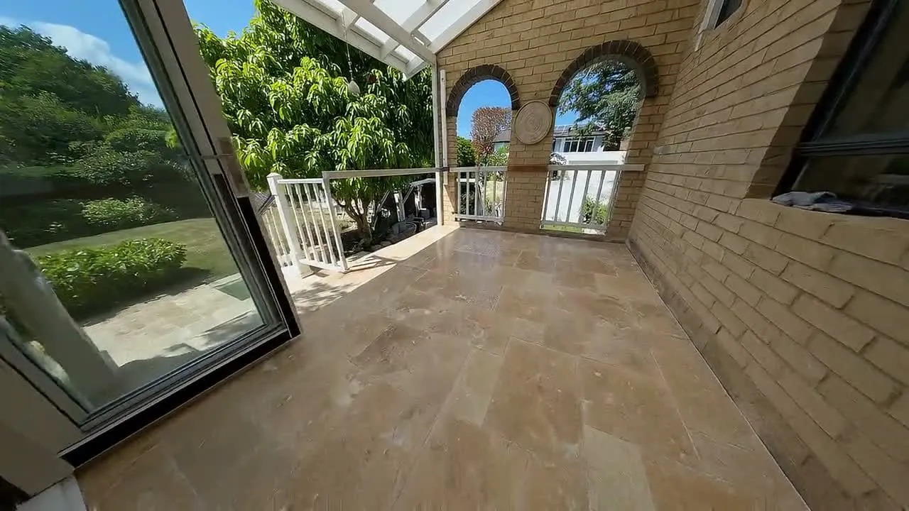 A travertine French-pattern floor under brick arches on a verandah.